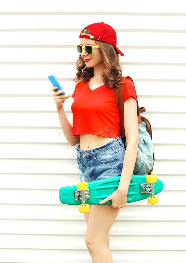Arbeiten Sie recht kühle lächelnde Frau mit Skateboard unter Verwendung des Smartphone über Weiß um stockbilder Arbeiten Sie recht kühle lächelnde Frau mit Skateboard unter Verwendung des Smartphone über Weiß um stockbilder