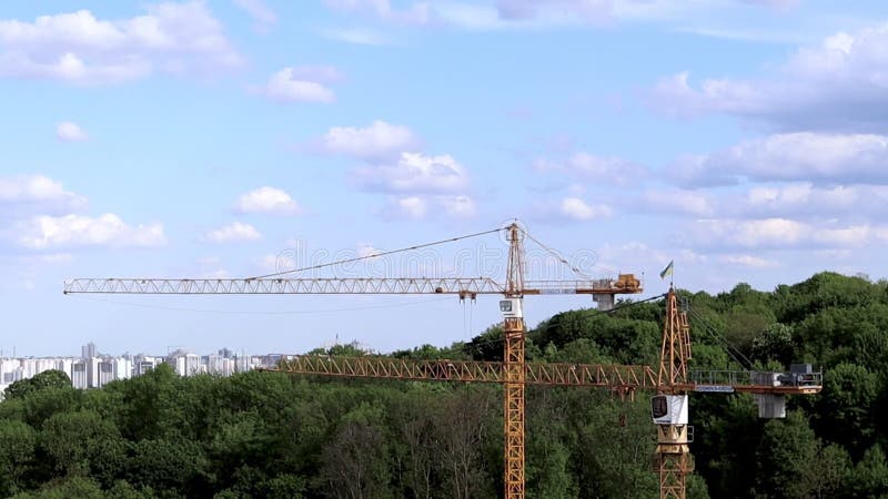 Arbeiter Bauturm hisst hohe gelbe Kräne auf einem modernen Gebäude im Bau gegen bewölkten Himmel und Stadt. städtisch