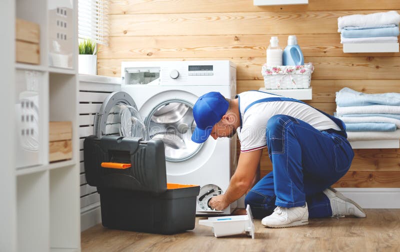 Arbeitersklempner repariert Waschmaschine in der Wäscherei stockfotos