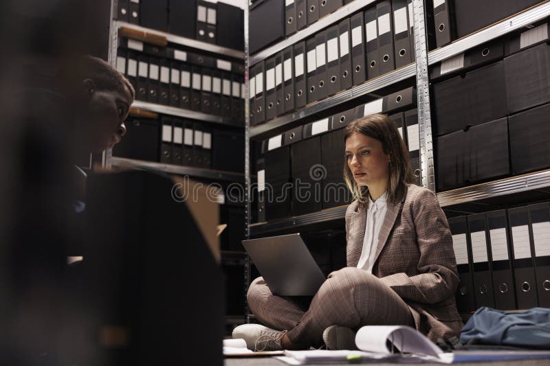 Depository workers discovering bookkeeping record in storage room, discussing administrative report. Diverse businesspeople analyzing management files, checking accountancy documents. Depository workers discovering bookkeeping record in storage room, discussing administrative report. Diverse businesspeople analyzing management files, checking accountancy documents