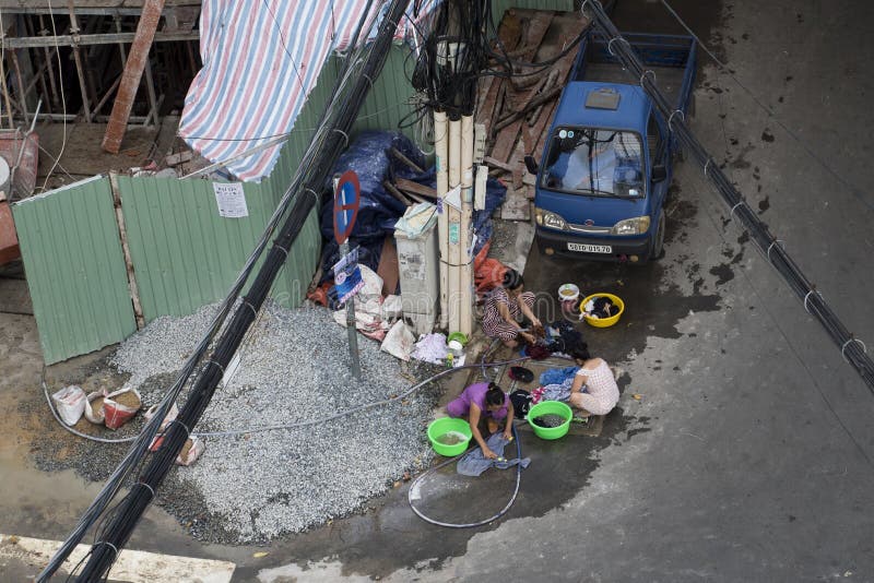Arbeitnehmerinnen tun die Wäscherei in der Straße nach der Tag-` s Arbeit an einer EigentumswohnungsBaustelle in Ho Chi Minh City stockfotografie Arbeitnehmerinnen tun die Wäscherei in der Straße nach der Tag-` s Arbeit an einer EigentumswohnungsBaustelle in Ho Chi Minh City stockfotografie