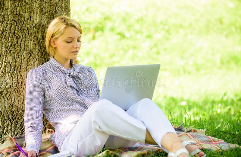 Work outdoors benefits. Education technology and internet concept. Woman with laptop computer work outdoors lean on tree trunk. Girl work with laptop in park sit on grass. Natural environment office. Work outdoors benefits. Education technology and internet concept. Woman with laptop computer work outdoors lean on tree trunk. Girl work with laptop in park sit on grass. Natural environment office.