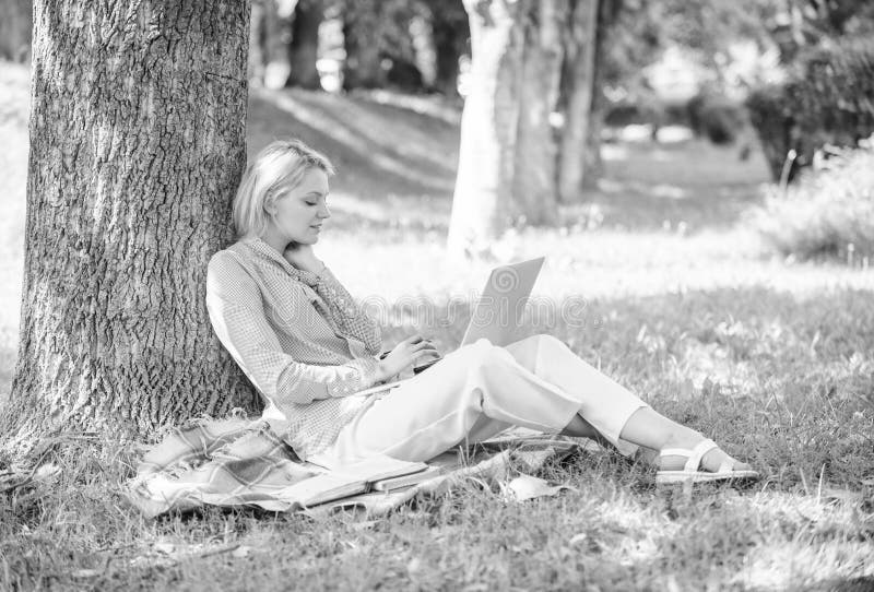 Work outdoors benefits. Woman with laptop computer work outdoors lean on tree trunk. Education technology and internet concept. Girl work with laptop in park sit on grass. Natural environment office. Work outdoors benefits. Woman with laptop computer work outdoors lean on tree trunk. Education technology and internet concept. Girl work with laptop in park sit on grass. Natural environment office.