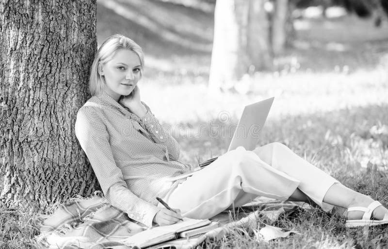 Work outdoors benefits. Woman with laptop computer work outdoors lean on tree trunk. Girl work with laptop in park sit on grass. Education technology and internet concept. Natural environment office. Work outdoors benefits. Woman with laptop computer work outdoors lean on tree trunk. Girl work with laptop in park sit on grass. Education technology and internet concept. Natural environment office.
