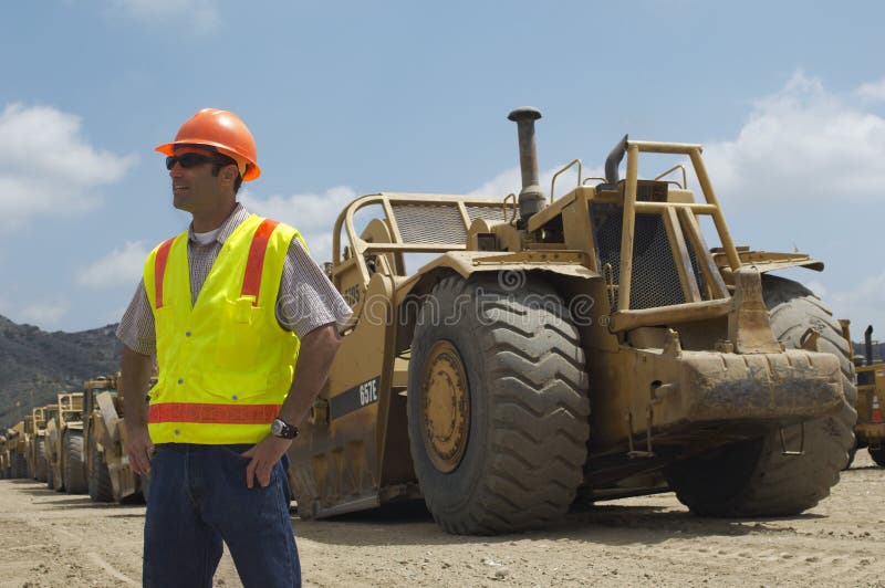 Male worker in reflective vest near trucks at landfill site. Male worker in reflective vest near trucks at landfill site