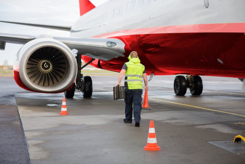 Arbeitskraft-tragender Verkehrs-Kegel und Keile durch Flugzeug auf Rollbahn lizenzfreie stockbilder Arbeitskraft-tragender Verkehrs-Kegel und Keile durch Flugzeug auf Rollbahn lizenzfreie stockbilder