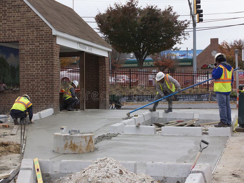 Baltimore, MDUSA - November 14, 2016: Workers finish cement at Maryland Transit Authority`s Paradise Loop bus stop on Frederick Rd. Baltimore, MDUSA - November 14, 2016: Workers finish cement at Maryland Transit Authority`s Paradise Loop bus stop on Frederick Rd.