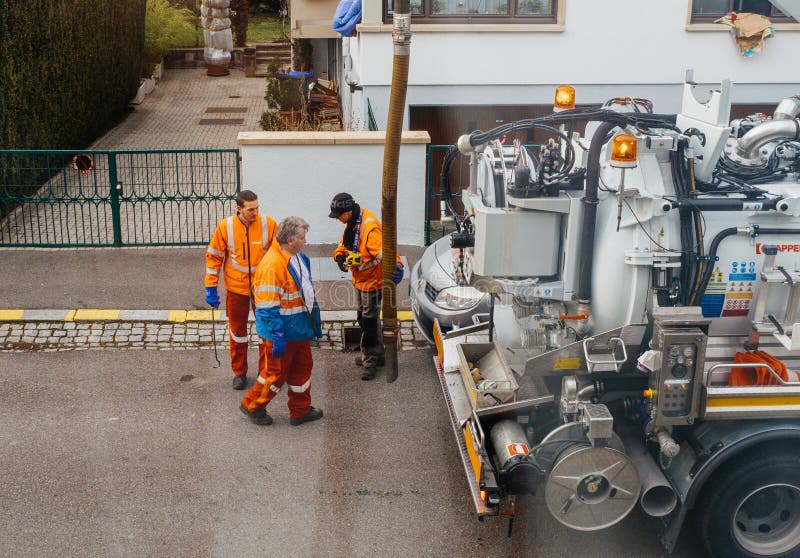 Arbetare som använder avloppsnätlastbilen och det stora röret som arbetar på cloggen arkivfoto Arbetare som använder avloppsnätlastbilen och det stora röret som arbetar på cloggen arkivfoto