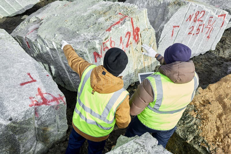 Arbetare som markerar stora bitar av granit royaltyfri fotografi