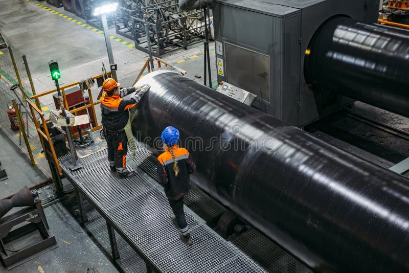 Arbetare undersöker det nya bestrukna röret i fabrik arkivbild Arbetare undersöker det nya bestrukna röret i fabrik arkivbild