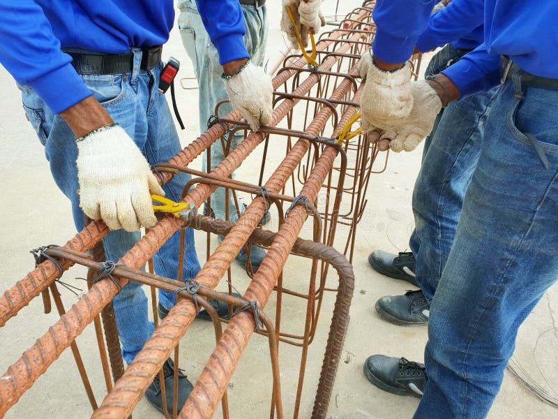 Arbetarhänder genom att använda ståltråd för säkrande av stålstänger med trådstången för förstärkning royaltyfri foto Arbetarhänder genom att använda ståltråd för säkrande av stålstänger med trådstången för förstärkning royaltyfri foto