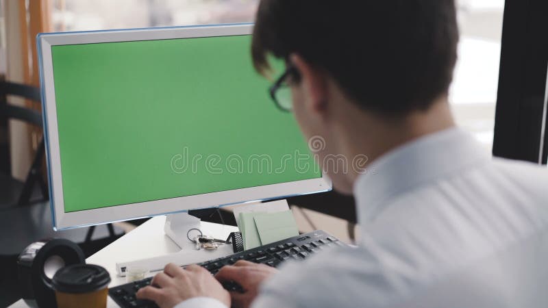 Arbeten för ung man med PC med den gröna skärmen och tangentbordet 4K