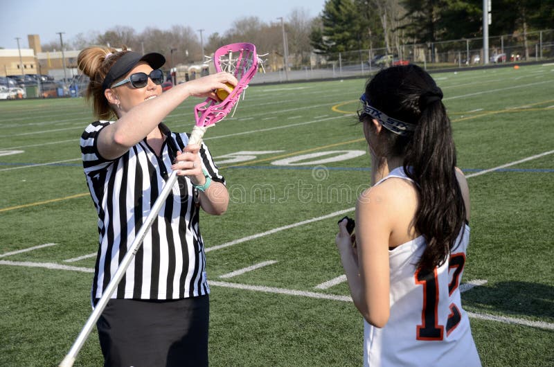 Arbitrez les contrôles un bâton de lacroose à un jeu de lacrosse de filles image stock Arbitrez les contrôles un bâton de lacroose à un jeu de lacrosse de filles image stock