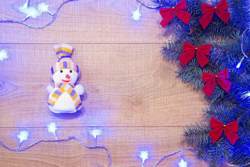 Arbre de nouvelle année/Noël avec les arcs rouges, jouet de bonhomme de neige, guirlande bleue sur le calibre en bois de fond photo stock Arbre de nouvelle année/Noël avec les arcs rouges, jouet de bonhomme de neige, guirlande bleue sur le calibre en bois de fond photo stock