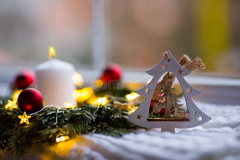 Arbre de Noël en bois décoratif avec les cerfs communs, la bougie blanche brûlante et la guirlande de sapin avec les boules rouge photo stock Arbre de Noël en bois décoratif avec les cerfs communs, la bougie blanche brûlante et la guirlande de sapin avec les boules rouge photo stock