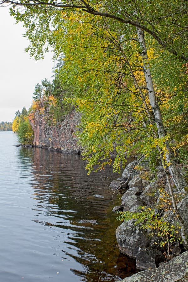 View of lake shore with trees and bluff in cloudy autumn weather. View of lake shore with trees and bluff in cloudy autumn weather.