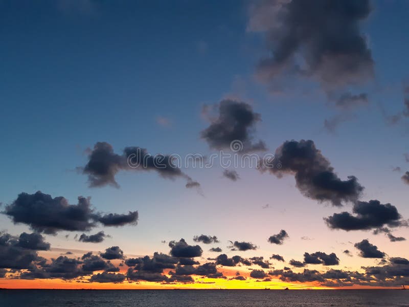 Arch av dramatiska moln i den solnedgångna himlen färgade i blått, rosa, gult och orange, över havet arkivbilder Arch av dramatiska moln i den solnedgångna himlen färgade i blått, rosa, gult och orange, över havet arkivbilder