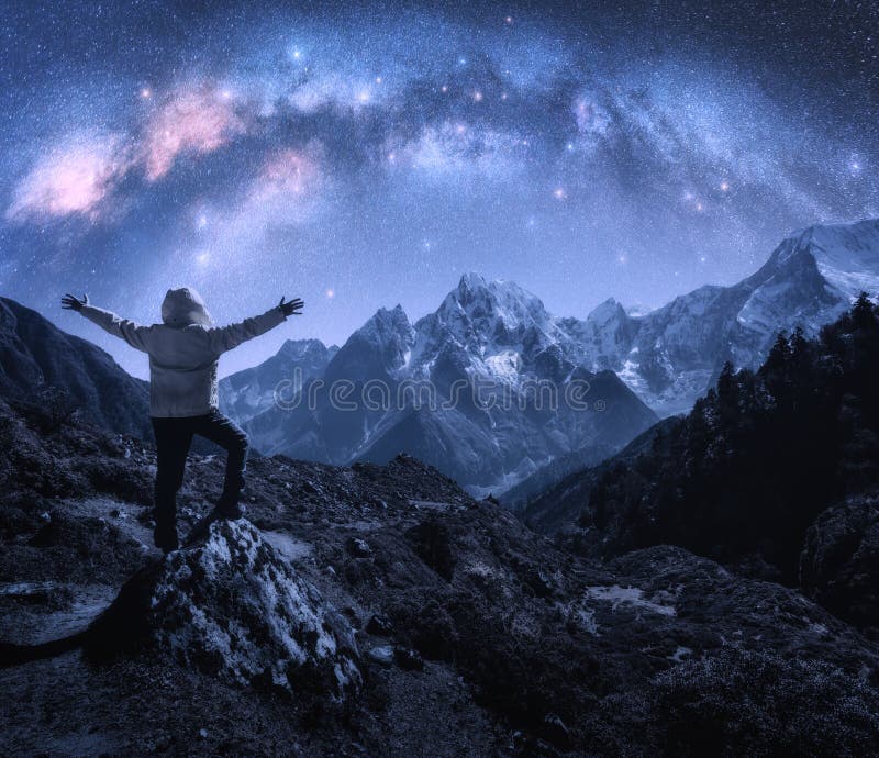 Arched Milky Way and sporty man on the stone and mountains