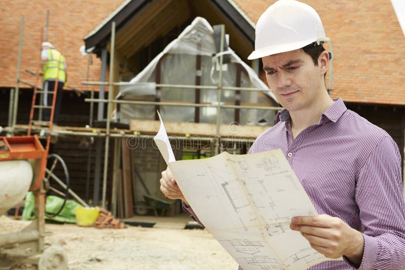 Architect On Building Site Looking At House Plans stock photography