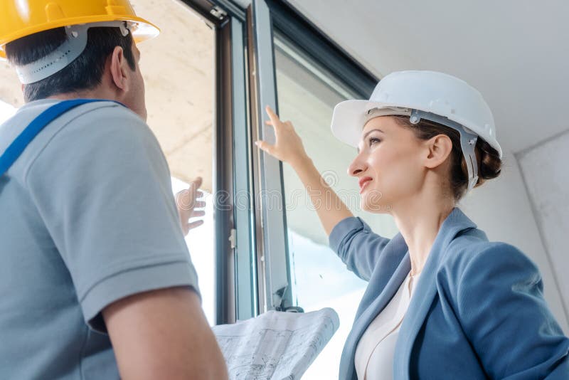 Architect and construction worker checking windows on site stock photography