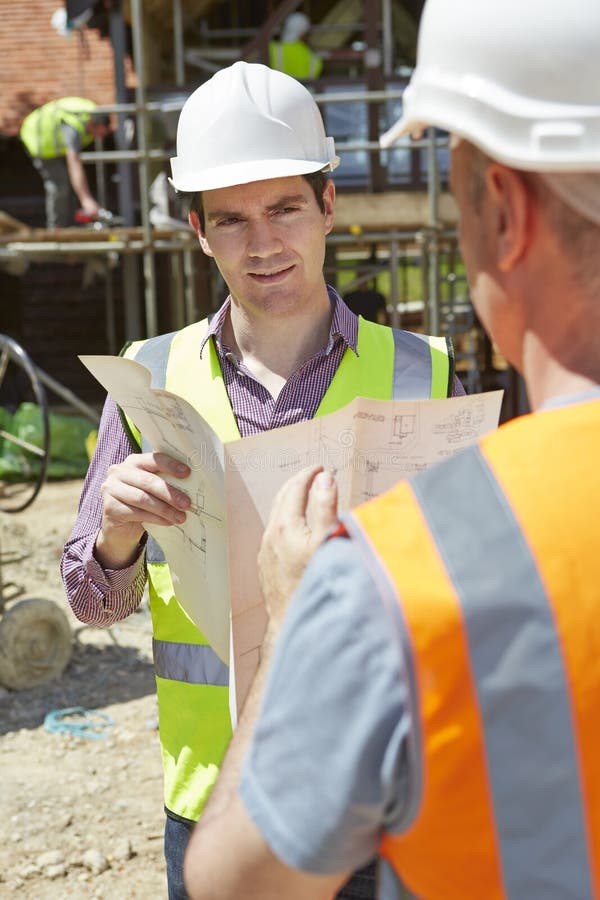 Architect Discussing Plans With Builders On Construction Site