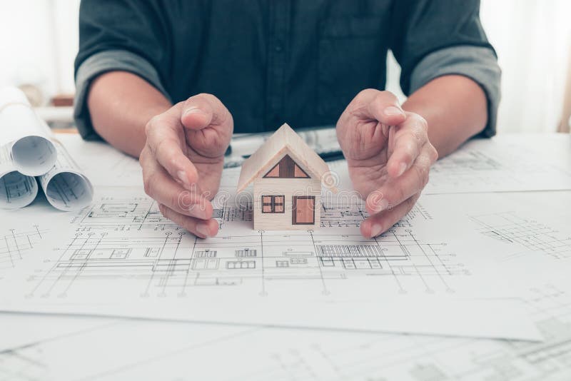 Architect Engineer Hands Hold and Protect Mini House Model on Blueprint. Protect House, Cost