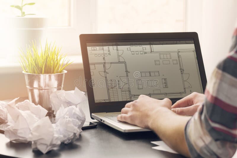 Architect, interior designer working on laptop with floor plans in office