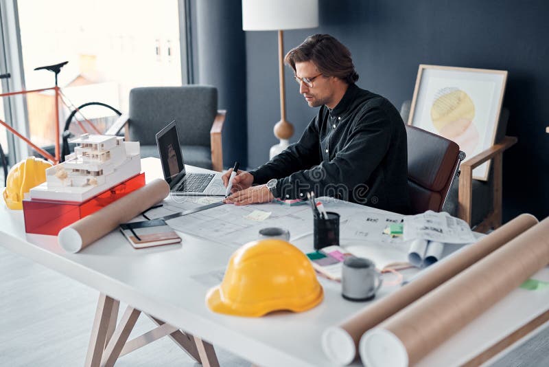 Architect, man and drawing on floor plan with blueprint for design layout, laptop and remodeling project. Engineering royalty free stock image