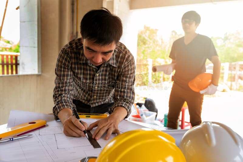 Architect Measuring Scale on Blueprint in Construction Site Stock Photo