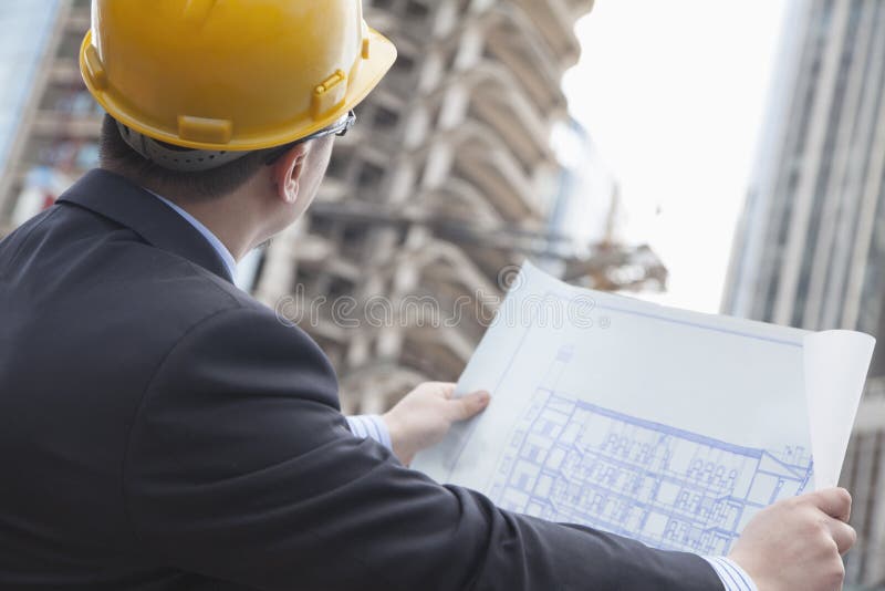 Architect on site looking at blueprints royalty free stock photo Architect on site looking at blueprints royalty free stock photo