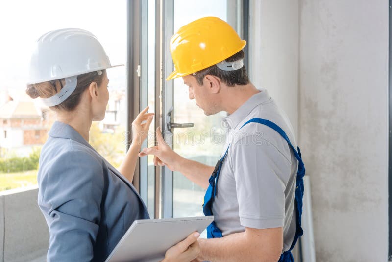 Architect and construction worker checking windows on site royalty free stock images