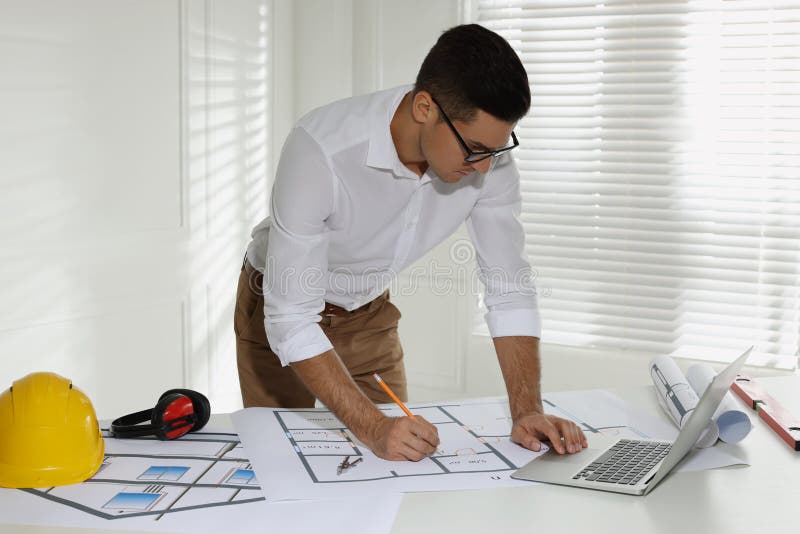 Architect working with construction drawings and laptop royalty free stock photo