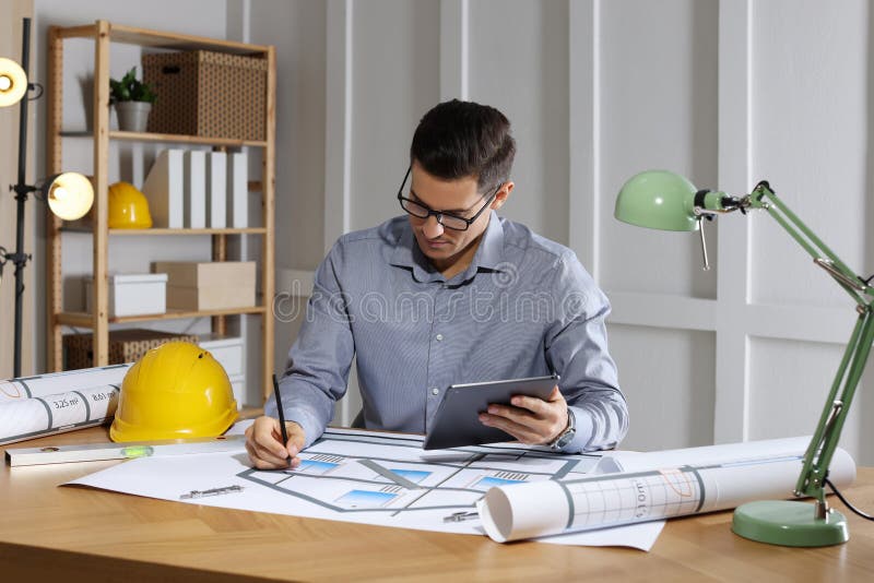 Architect Working with Construction Drawings and Tablet Stock Photo