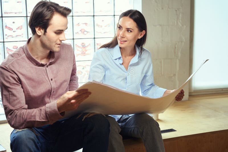 Architects Analyzing Rolledout Technical Drawing in Their Hands Stock