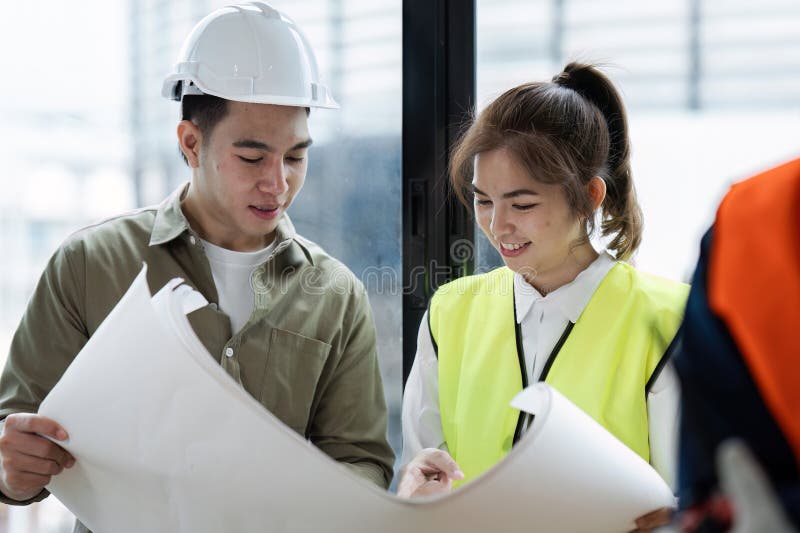 Architects Collaborating on Blueprint Plans at Construction Site with Safety Gear royalty free stock photo
