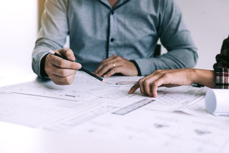 Architects or engineering working with blueprints and discussing project together at the meeting in the office royalty free stock image