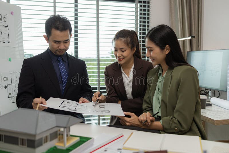 Architects work with engineers and contractors in the office to check the accuracy of the first draft plan, blueprint on the desk stock image