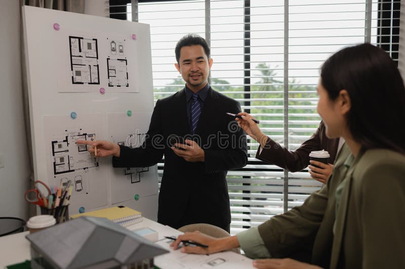Architects work with engineers and contractors in the office to check the accuracy of the first draft plan, blueprint on the desk stock photography
