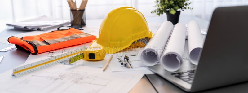 Architectural designed blueprint layout and engineer tools on table. Insight. Architectural designed building blueprint layout and engineer tool for designing blueprint with contractor project document on engineer workspace table in office with safety helmet or hardhat.