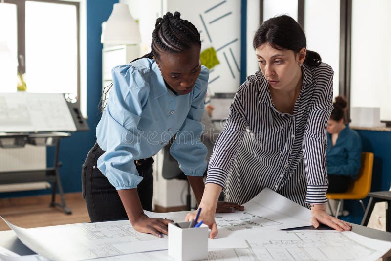 Architectural team of multi ethnic women plan sketch stock photos