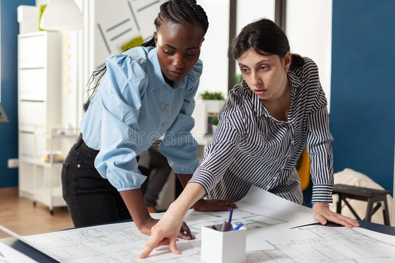 Architectural team of multi ethnic women plan sketch stock photos