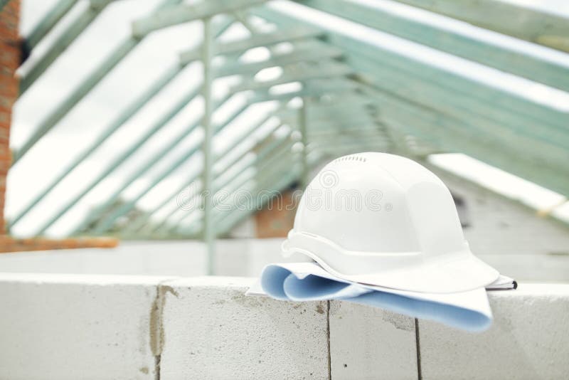 Architecture and House building concept. Hard hat with house blueprints on aerated concrete blocks on background of unfinished