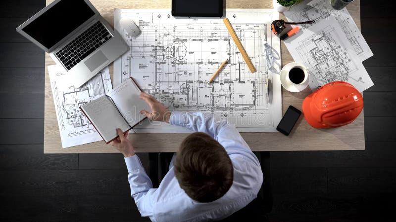 Architekt sprawdza notatki robi w jego notatniku dodawać je rysować budynek obrazy royalty free Architekt sprawdza notatki robi w jego notatniku dodawać je rysować budynek obrazy royalty free