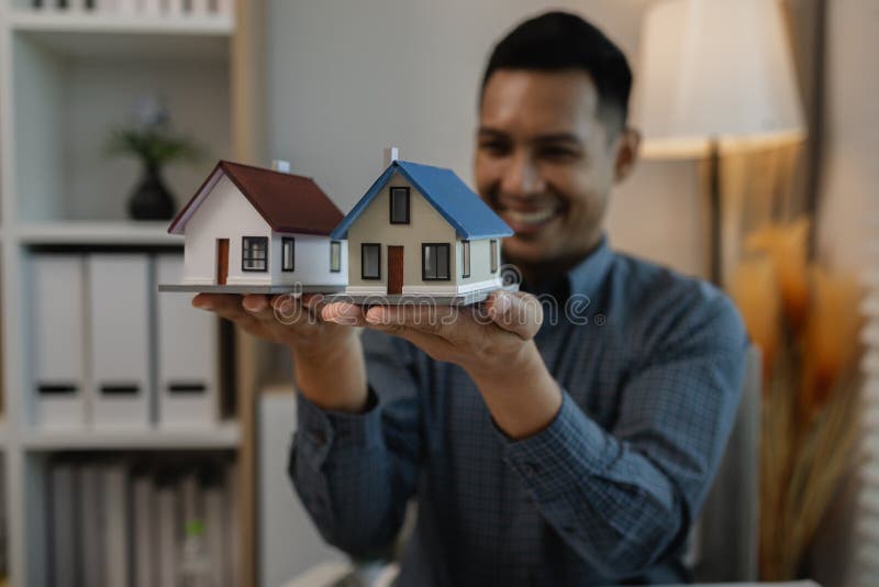 Architekten zeichnen und gestalten Hausunternehmer oder Architekten mit dem Modell eines Hauses, das in einem Architektenportrait. Architekt Zeichnung und Gestaltung des Hausgeschäftes oder Architekten mit dem Modell eines Hauses im Büro Portrait des Architekten am Arbeitsplatz Architekten Blick auf Baumodell im Büro
