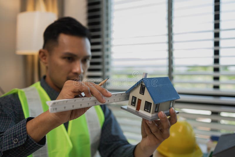 Architekten zeichnen und gestalten Hausunternehmer oder Architekten mit dem Modell eines Hauses, das in einem Architektenportrait lizenzfreies stockbild