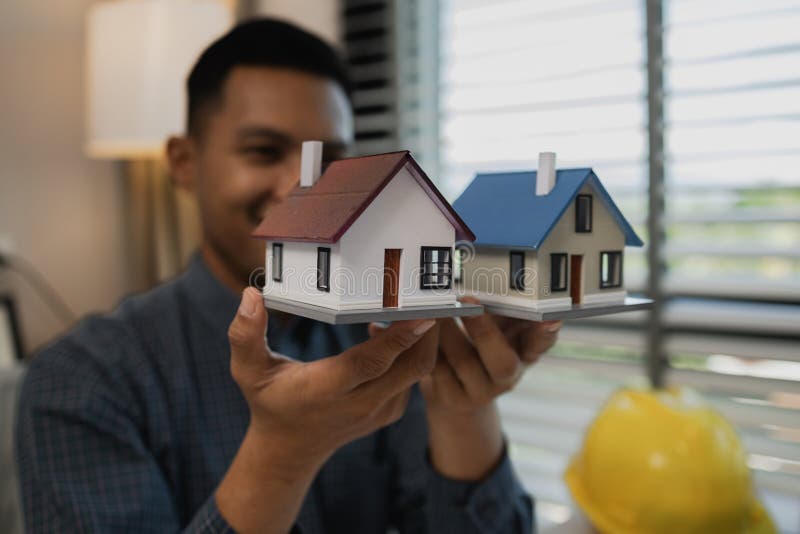 Architekten zeichnen und gestalten Hausunternehmer oder Architekten mit dem Modell eines Hauses, das in einem Architektenportrait lizenzfreie stockfotos