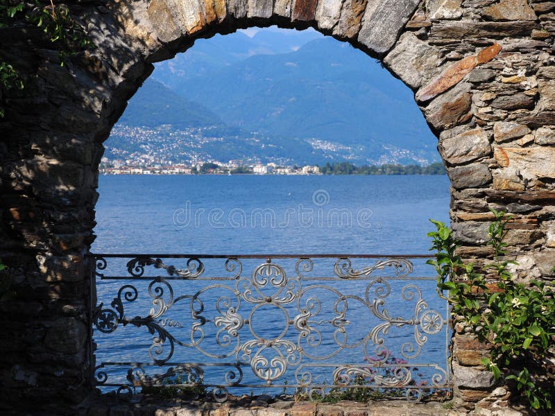 Arco pedregoso en la isla de Brissago en Suiza con la opinión alpina escénica sobre el lago suizo Maggiore fotografía de archivo libre de regalías Arco pedregoso en la isla de Brissago en Suiza con la opinión alpina escénica sobre el lago suizo Maggiore fotografía de archivo libre de regalías