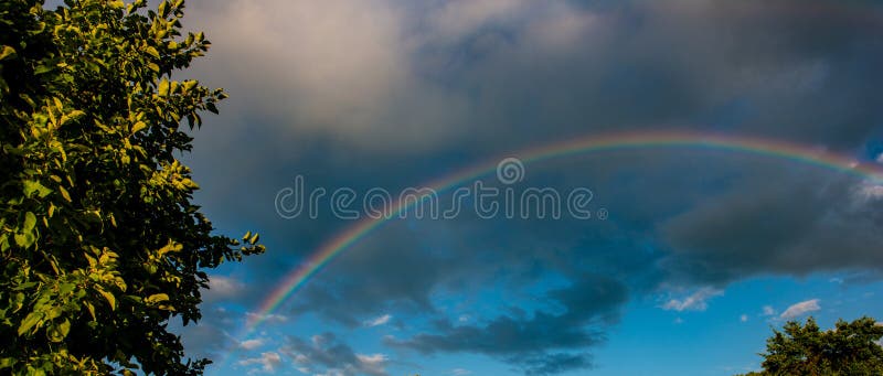Arco-íris na chuva e no por do sol no campo fotografia de stock