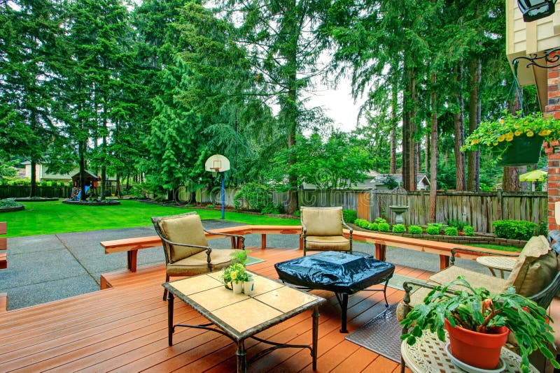 Backyard patio area with antique table set and fire pit. View of basketball court and green lawn. Backyard patio area with antique table set and fire pit. View of basketball court and green lawn