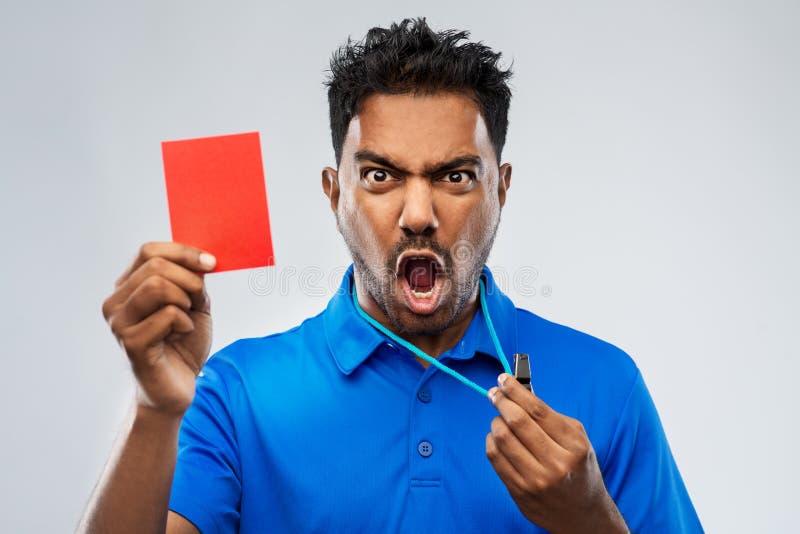 Sport, caution, game and football concept - angry indian male referee with whistle and showing red penalty card. Sport, caution, game and football concept - angry indian male referee with whistle and showing red penalty card